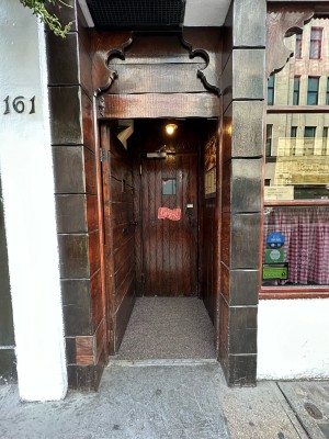 First wooden door. Push black metal knob on right to open.