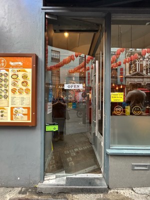 Preceding single clear glass door with vertical silver metal handle along right. Push to open.