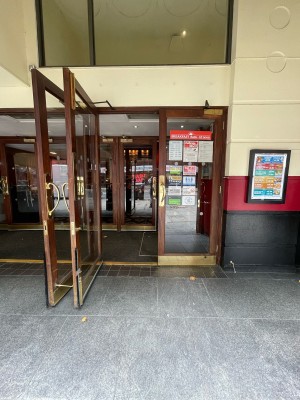 First set of double glass doors with brown wooden frame ahead. Gold handles to centre. Pull to open.