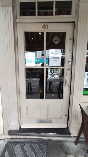 Single white wooden door with glass panels. Silver metal vertical handle along right. Push to open.