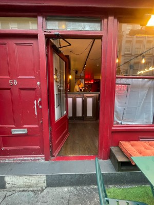 Glass door with red frame ahead. Silver metal panel to right. Push to open from right.