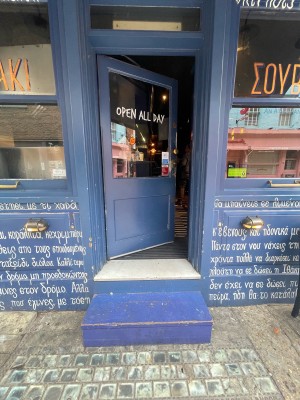 Wooden and glass blue door ahead. Gold knob and handle to right. Push to open from right.