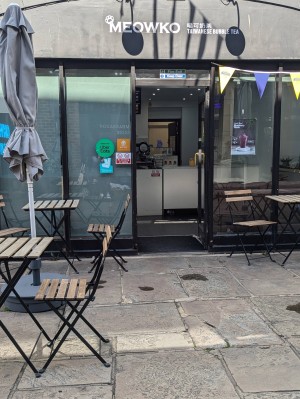 Front entrance.
Level access.
Push to open manual door.
Tables and chairs outside on either side of the door.