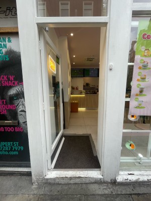 Glass door with white frame ahead. Metal panel to right. Push to open.
