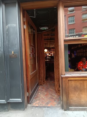 Glass door with brown wooden frame. Golden pad on right. Push to open. Brown curtains after doorway. Pull outwards from centre to open.
