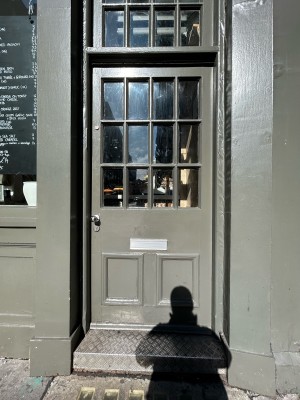 Single grey wooden door with glass panels. Silver doorknob on left, twist and push to open.