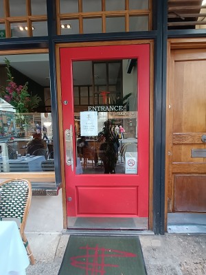 Glass door with red frame. Silver metal handle on left. Push to open.