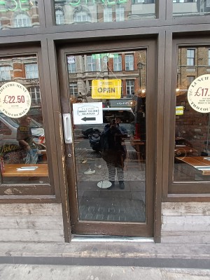 Glass door with brown frame. Silver, metal handle on left. Push to open.