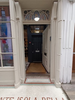 White door with silver, metal, vertical handle along left. Push to open.