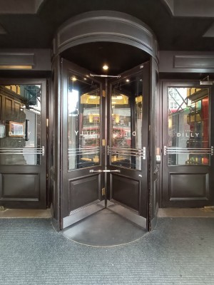 Glass doors with brown frames. Silver metal handles in middle. Push to right to open.