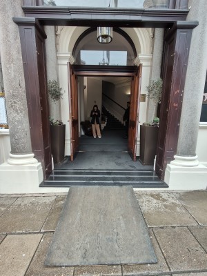 Facing brown framed entrance archway. Path ahead to entrance door at back.