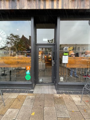 Black wood-framed glass door ahead. Push silver handle on right to open.