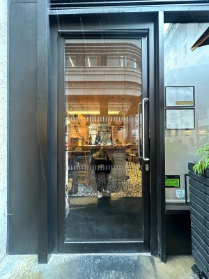 Glass door with black frame. Silver vertical handle on right, push to open.