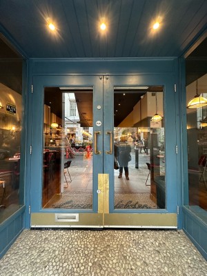 Glass doors with blue frame. Gold vertical handle in centre, pull to open.