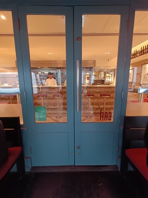 Glass doors with blue frame. Silver, metal vertical handle in middle. Pull to open.