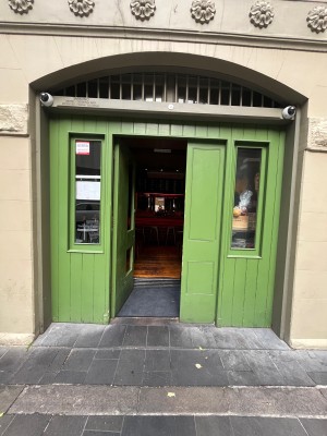Green wooden door with glass panels. Push from right to open.