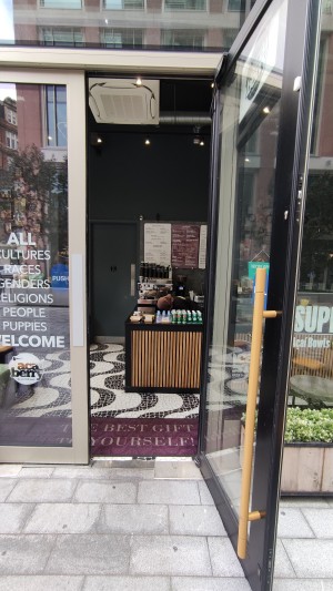 Glass door with black frames ahead. Pull to left via metal vertical handle.