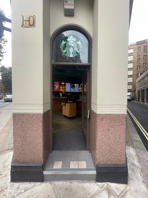 Glass door with wooden brown frame ahead. Silver metal handle to top left. Push to open.