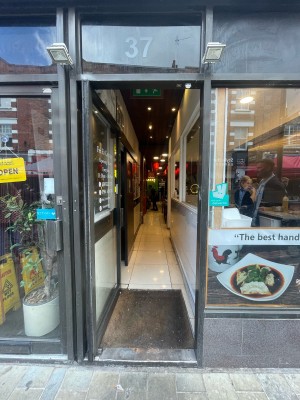 Glass door with black wooden frame ahead. Black handle to right. Push to open.