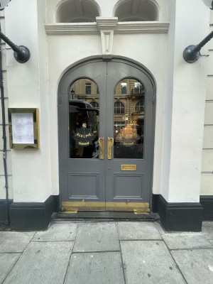 Double glass and wooden grey doors ahead. Gold metal handles in centre. Pull to open.