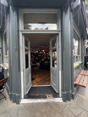 Double grey wooden doors with glass windows. Push metal panels in centre of doors to open.