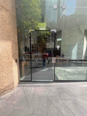 Glass door with black frame. Turn handle and pull from right to open.