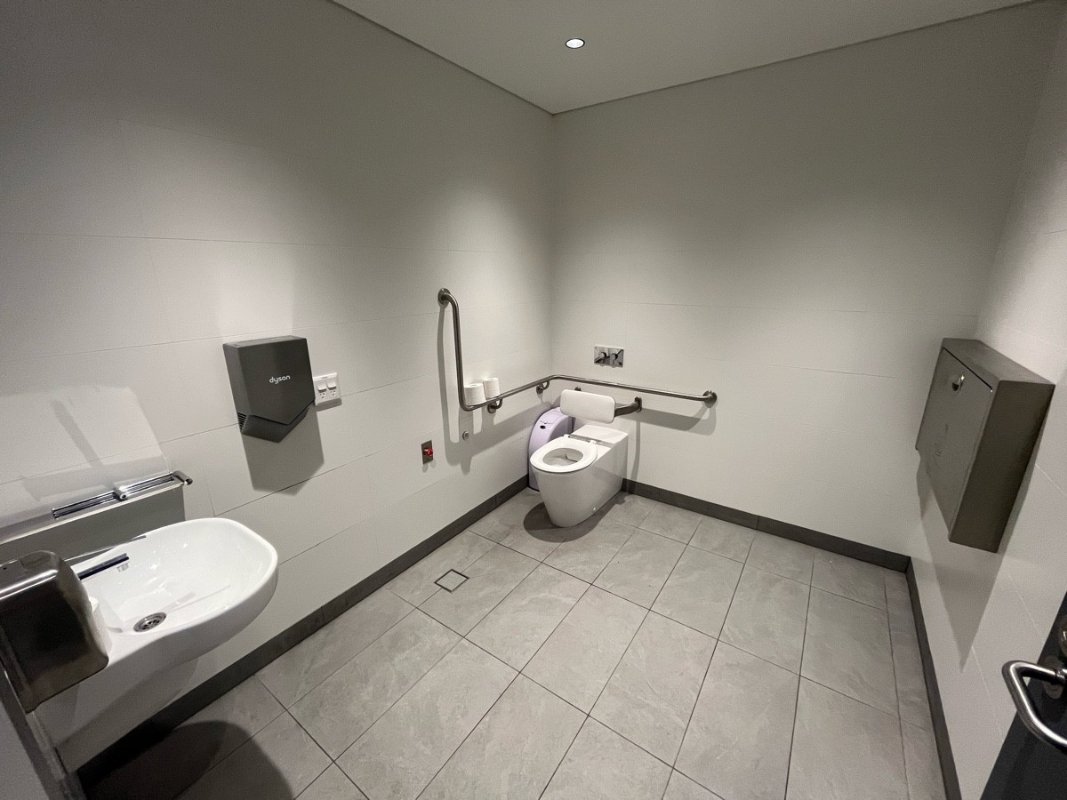 From door facing straight. Baby change on right wall. Toilet on back wall to left. Emergency button on left wall. Sink on near left wall.