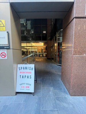 Built in ramp leading to door. Door on right wall ahead. Signage obstructing on left.