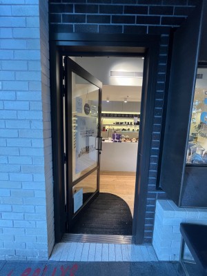Glass door with grey metal frame. Push from right.