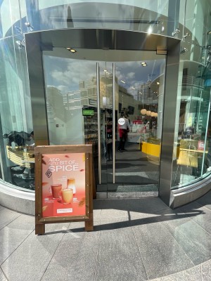 Double glass doors ahead. Silver vertical metal handles to centre. Push to open. Sandwich board in front of left door.