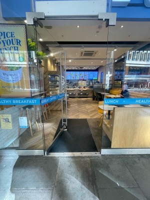 Glass door ahead. Silver vertical metal handle to right. Push to open.