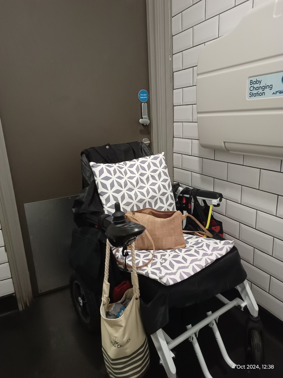 View of my chair from the toilet, not a lot of room, took a 3 point turn to get back facing the door. Baby table. Small stiff door look handle.