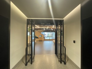 Double glass doors in brown metal frames. Scan card to right of doors. Doors swing outward from center. Brown metal fences either side.