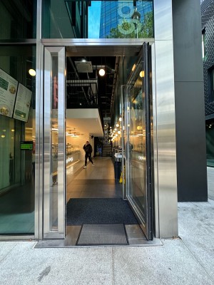 Glass door with silver frame. Silver metal vertical handle on left, push to open.