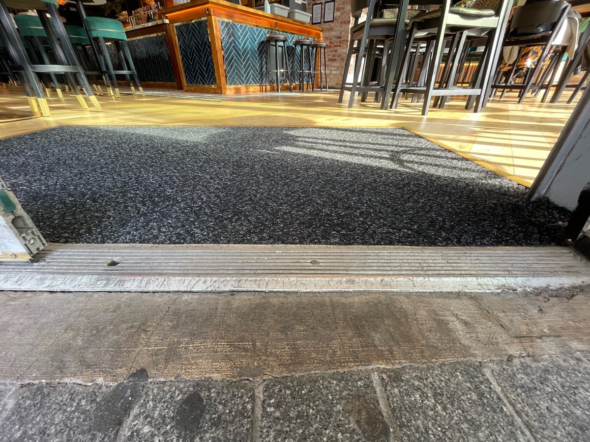 Metal bump along centre of door. Black doormat immediately after door.