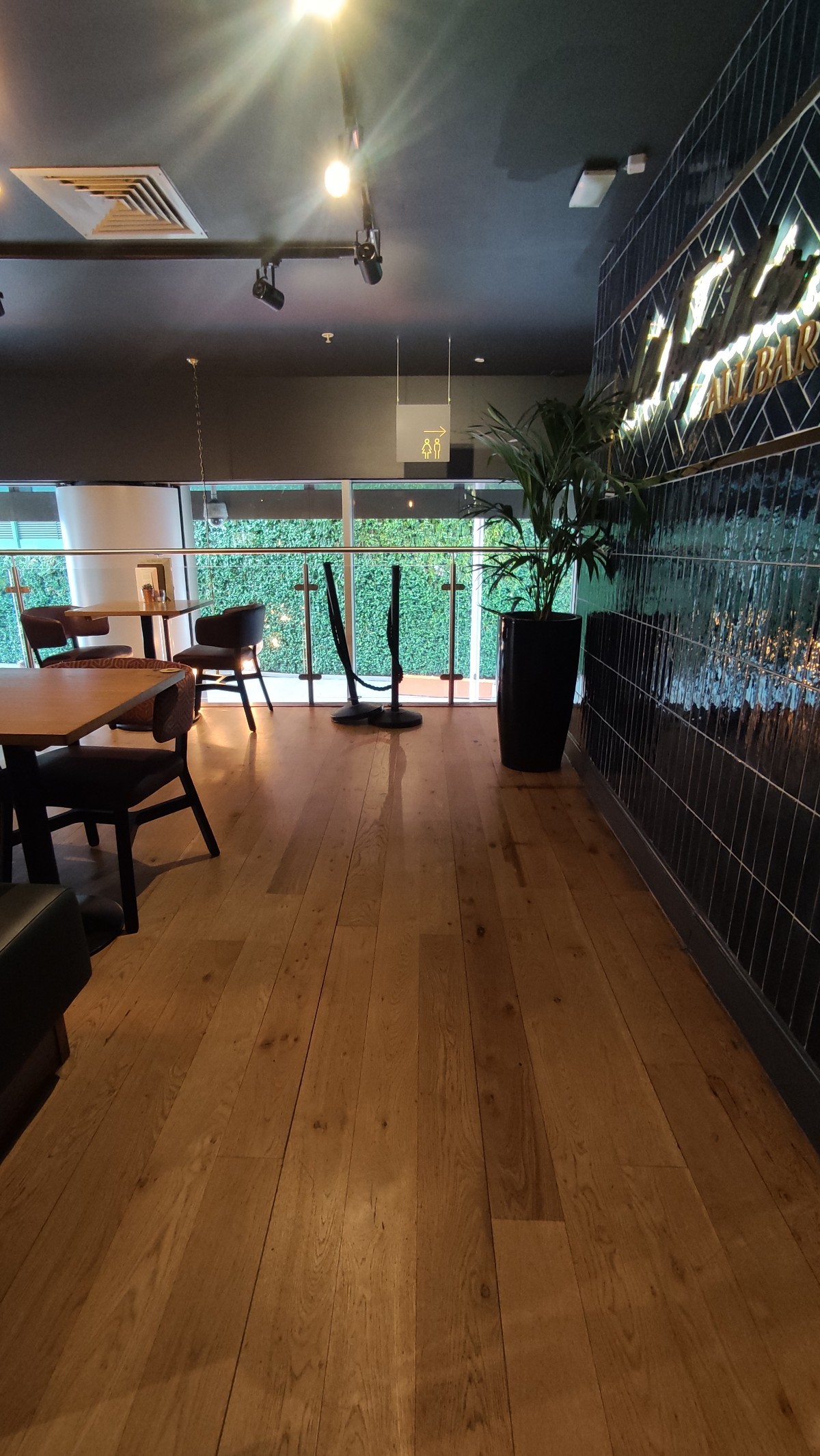 From top of staircase facing left. Half booths to left. Path ahead. Planters to back right.