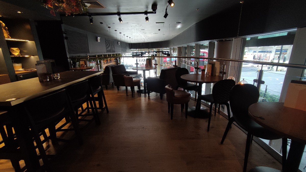 From end of path facing straight. High table with stools along left. Tables and chairs along right. Tables with arm chairs at the back.