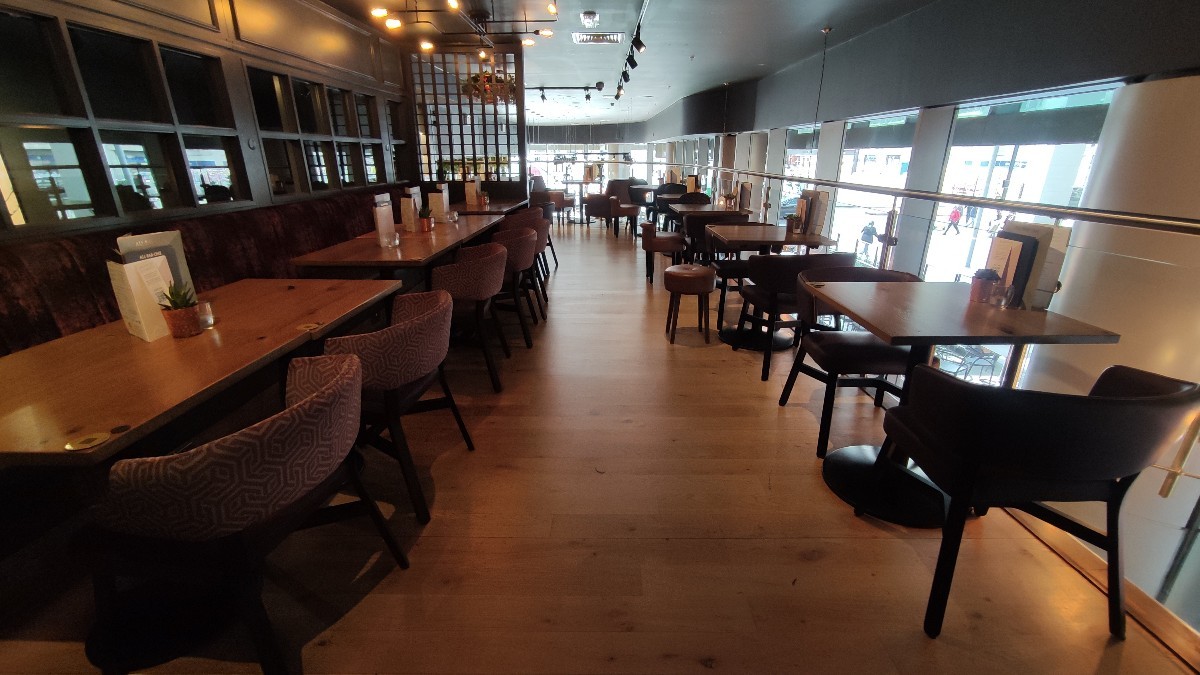 From planter facing left. Halfbooth with chairs along left. Path in centre. Tables with chairs along right.