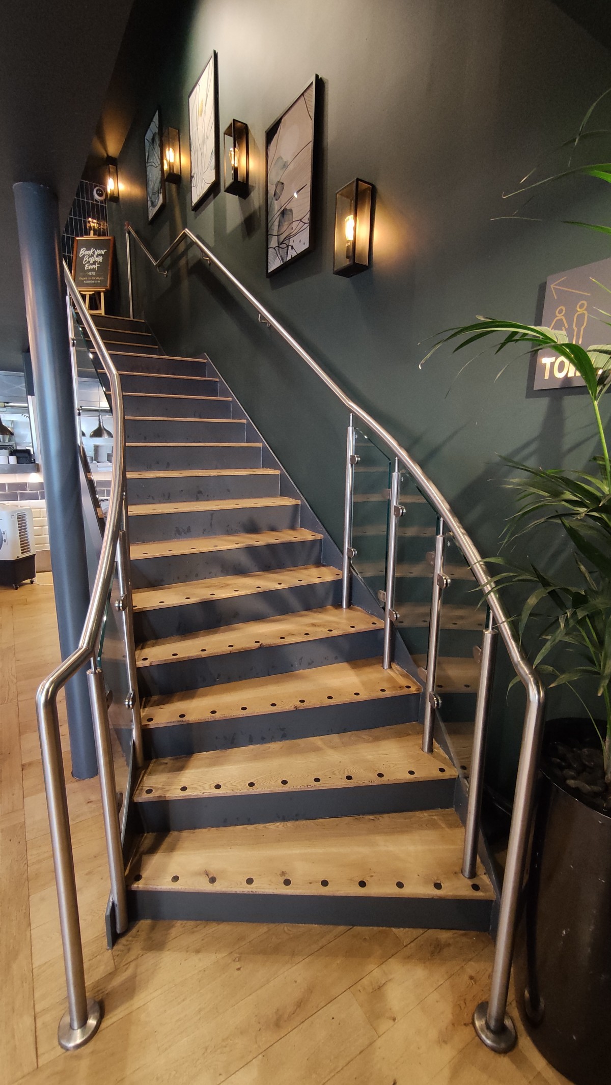 From end of path facing left. Staircase ahead. First four steps curve left. Metal handrails on both sides.