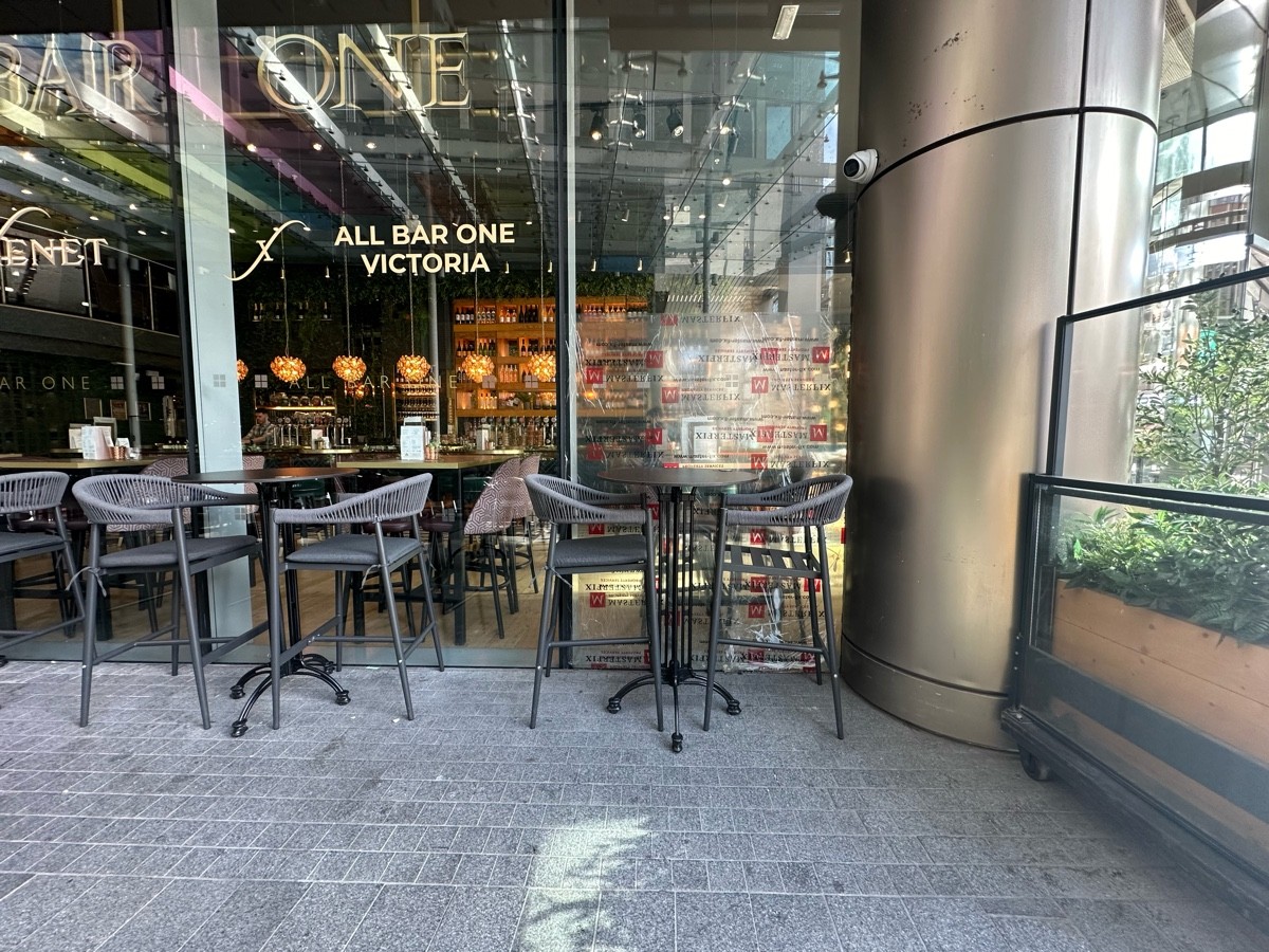 From opening, facing right. Glass wall and planter on right. High tables and stools along back wall.