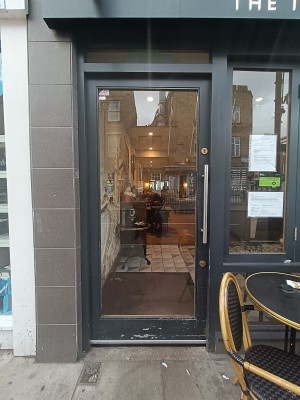 Glass door with silver, vertical handle on right. Push to open.