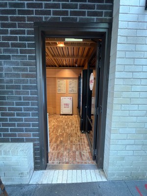 Glass door with grey metal frame. Push from left to open.