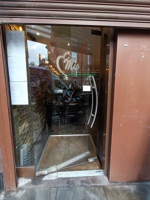 Glass door with curved, silver, handle along right. Push to open.