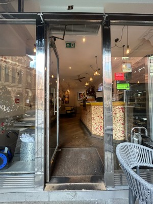Single glass door with silver metal frame and handle on right. Push to open.