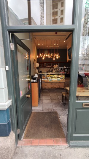 Glass door with dark green frames ahead. Push to right to open.