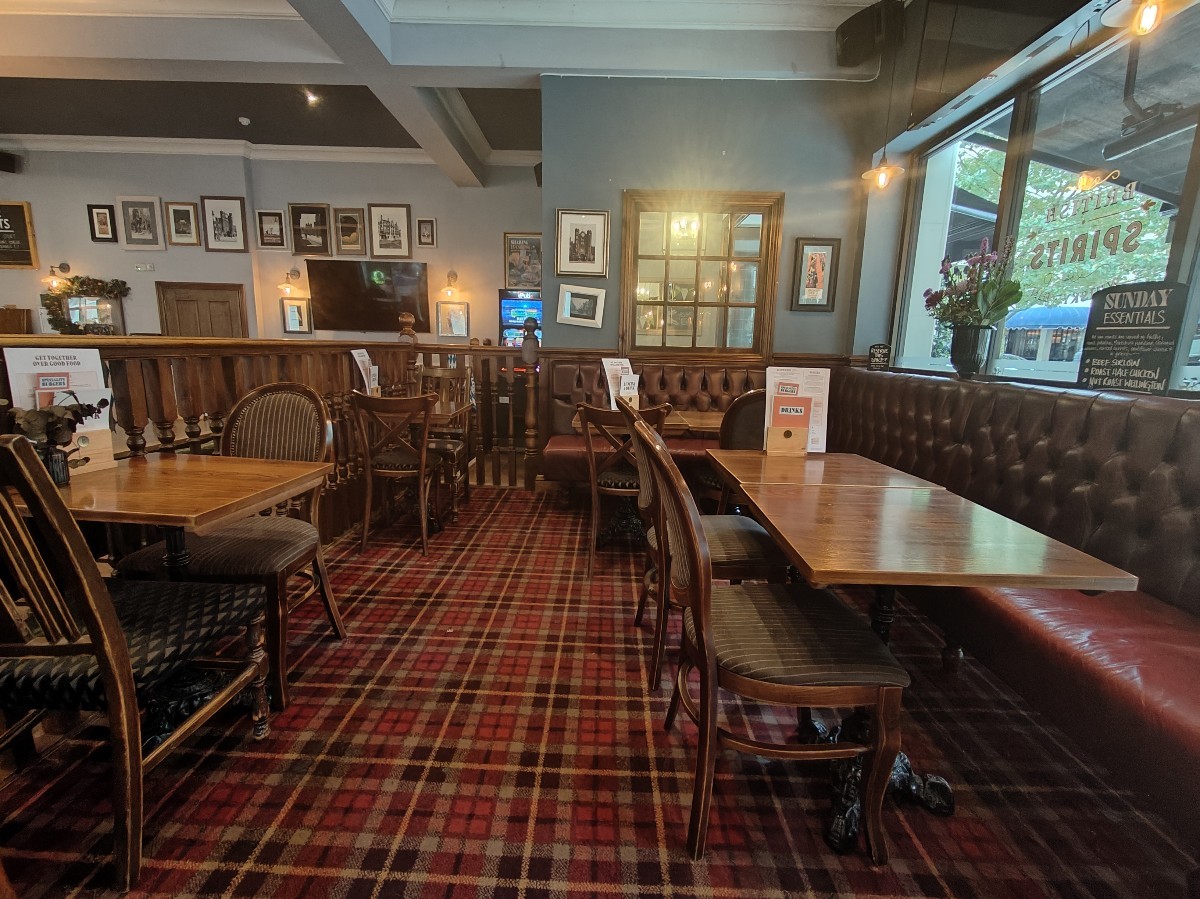 From top of steps facing left. Half booth along right and back right. Straight path ahead. Tables and chairs along left.