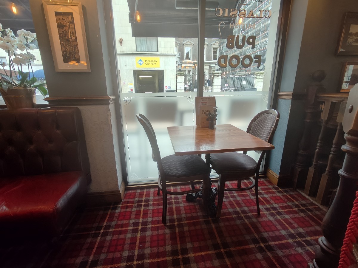 From top of steps facing right. Table and chairs along back glass wall. Half booth on left.
