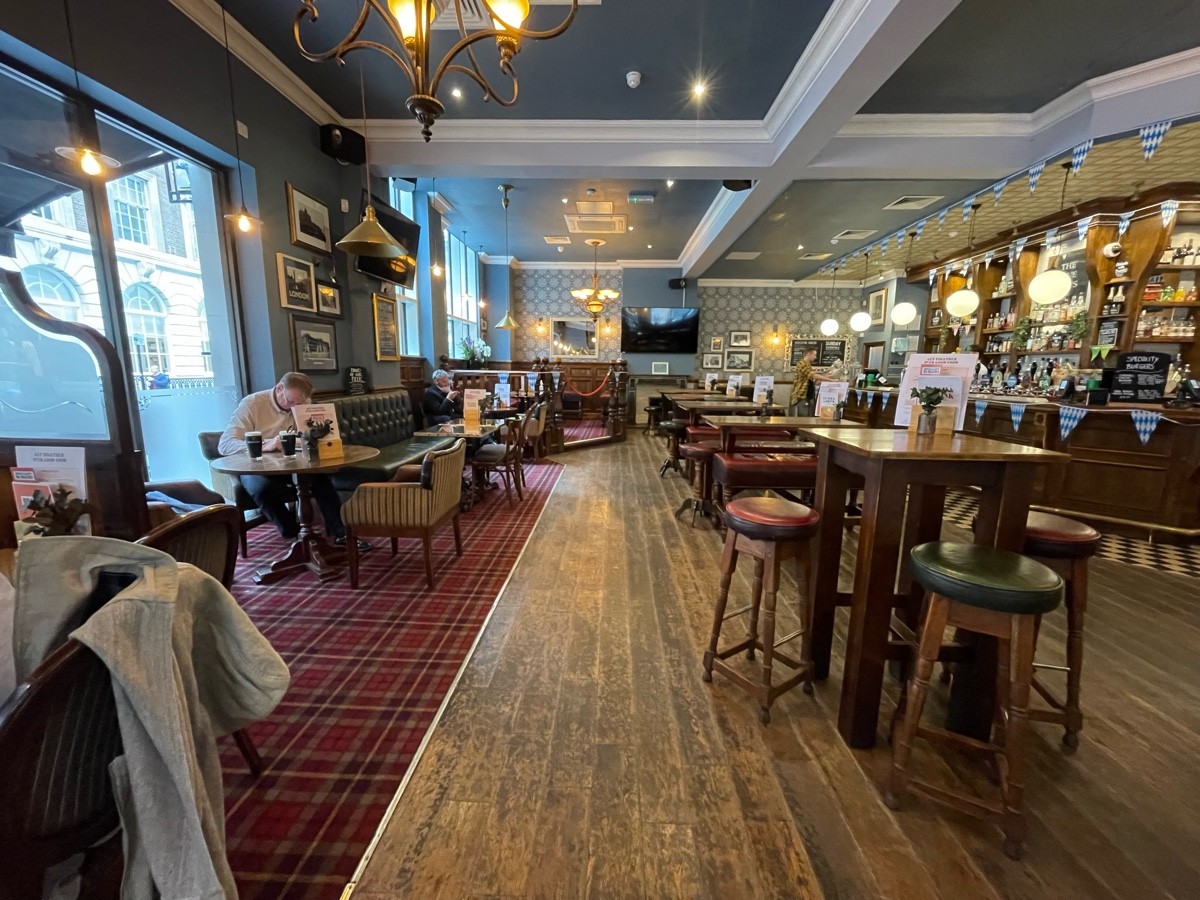 From end of half booths, facing straight. Armchairs and table to back left. Half booths with chairs beyond. Path ahead. High table and stools on right