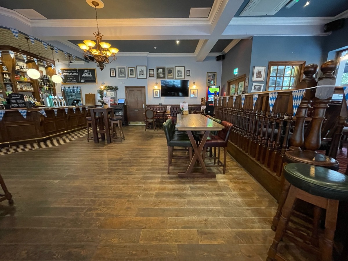 From left of stairs, facing right. Banister along right. Path ahead. Long high table and stools ahead.