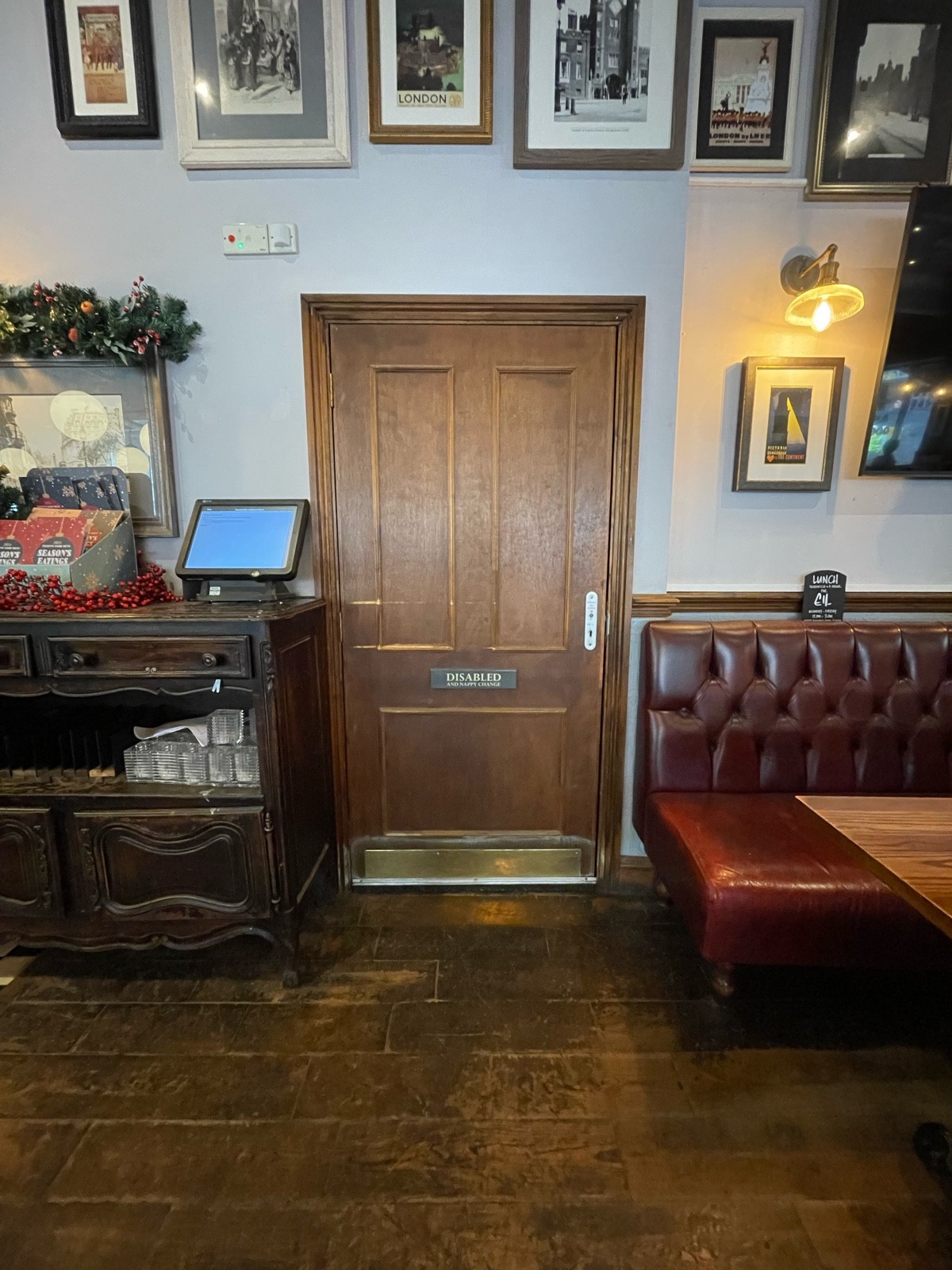 From right side of bar, facing straight. Wooden bathroom door ahead. Silver radar keyhole on right, pull to open. Seating on right. Staff desk on left
